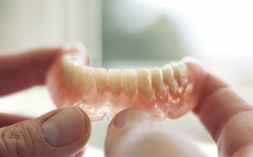 person holding a set of dentures near a window