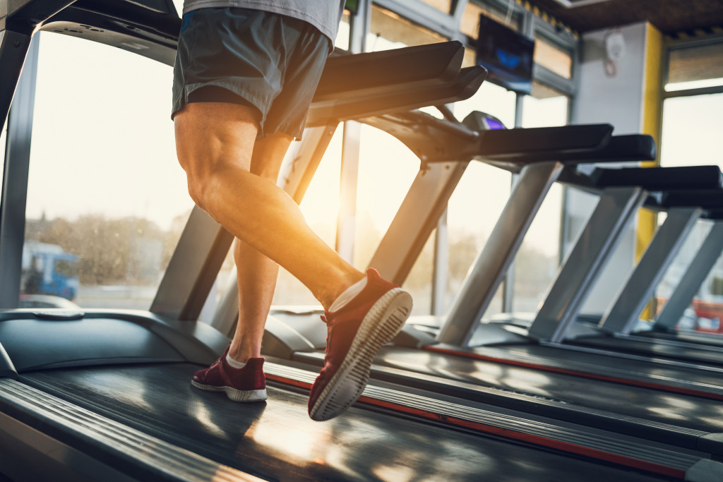 man running in a threadmill at a gym in early morning