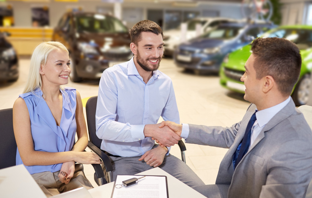 Sales executive connecting with customers at a car dealership.