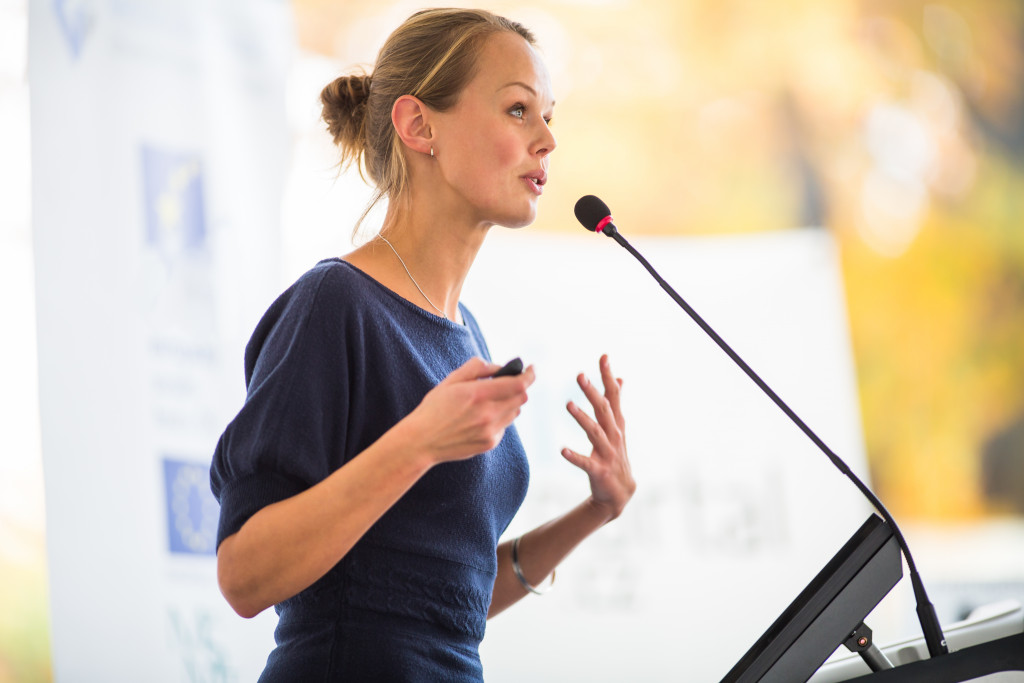 Young businesswoman giving a presentation on stage during a conference.
