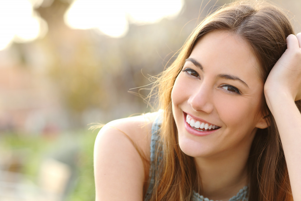 woman with white teeth in a park smiling